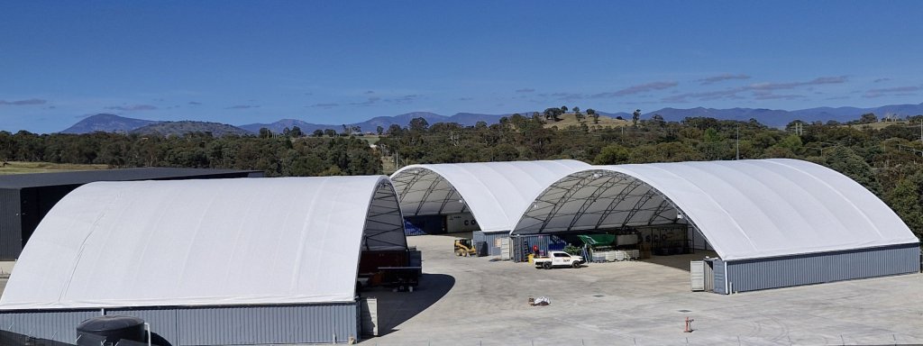 3 container domes with cars parked in front